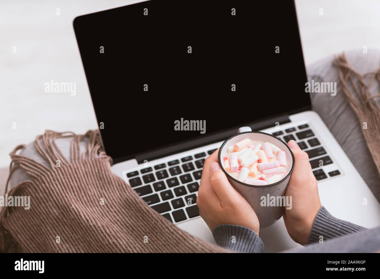 Female looking at laptop and drinking tasty cocoa Stock Photo