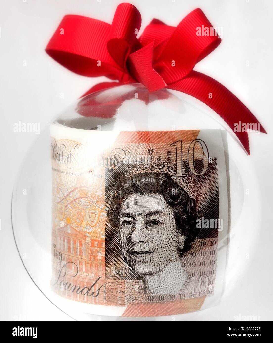 A ten pound note in a clear Christmas bauble. Stock Photo