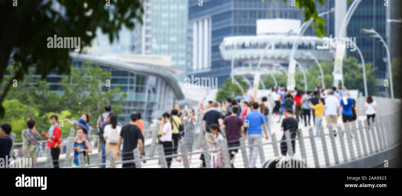 (Defocused picture) Blurred crowd of local people and tourists walking on a bridge in Singapore. Stock Photo