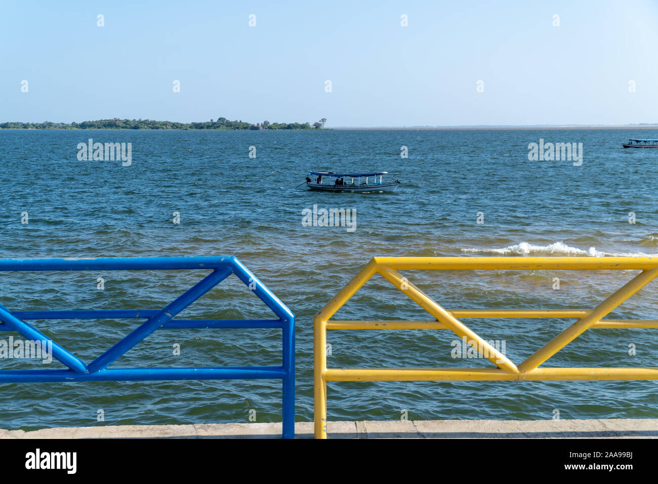 Wooden motor boat sailing on Tapajos river on sunny summer day in amazon with colorful sidewalk grid of Santarem city. Travel, tourism, climate change Stock Photo