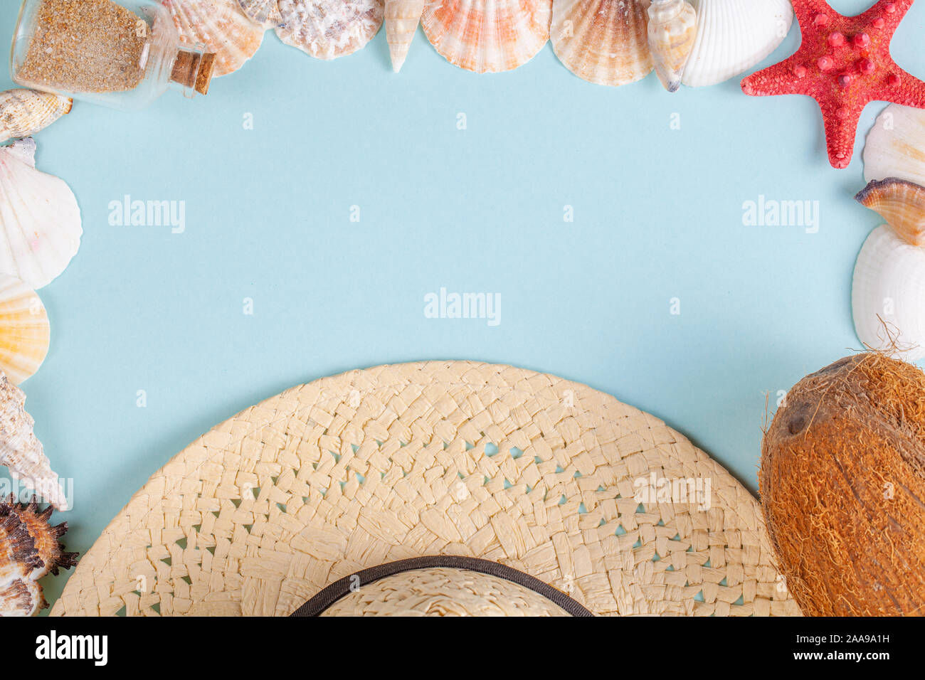 Coconut, starfish, shells, straw hat and bottle with sand on blue ...