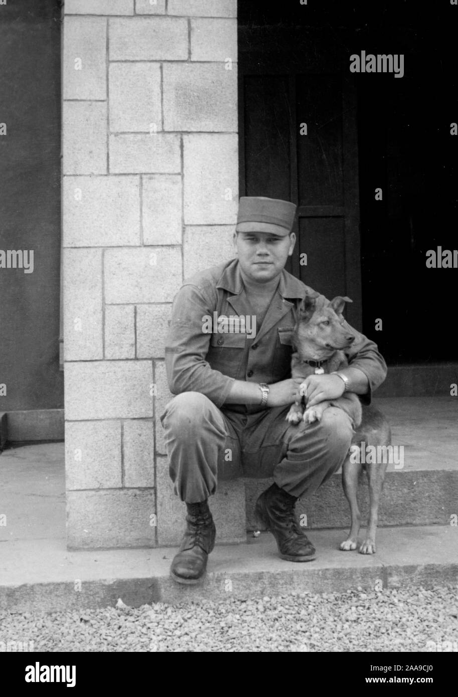 US Army soldier holds  a dog on base during the Korean War, ca. 1953. Stock Photo