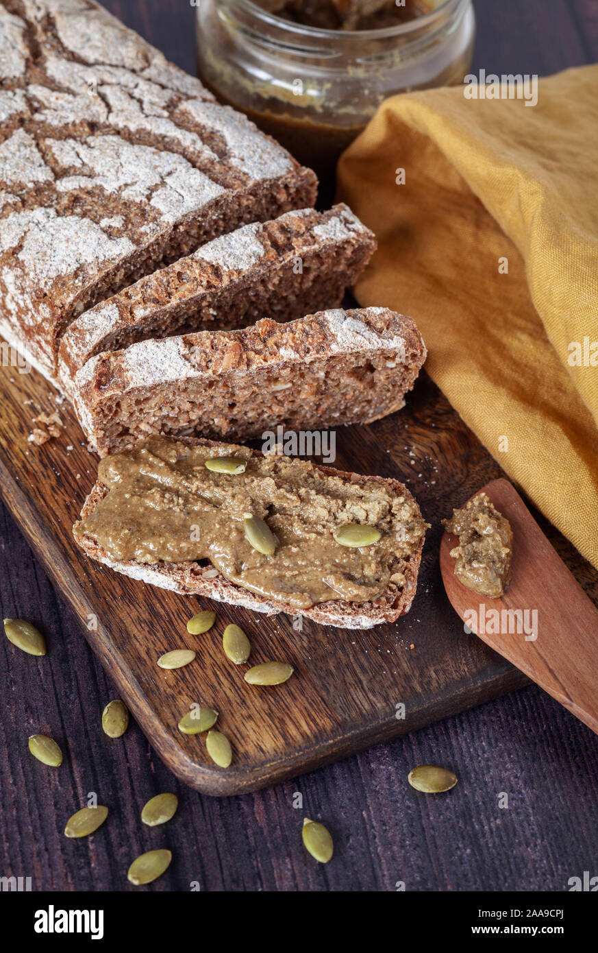 Fresh home baked rye bread with homemade pumpkin seed spread on wooden board Stock Photo
