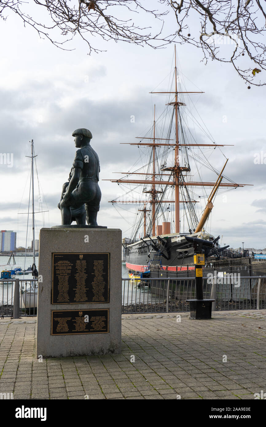 The Mud lark statue on The Hard, Portsea, Portsmouth, UK with HMS Warrior in the background Stock Photo