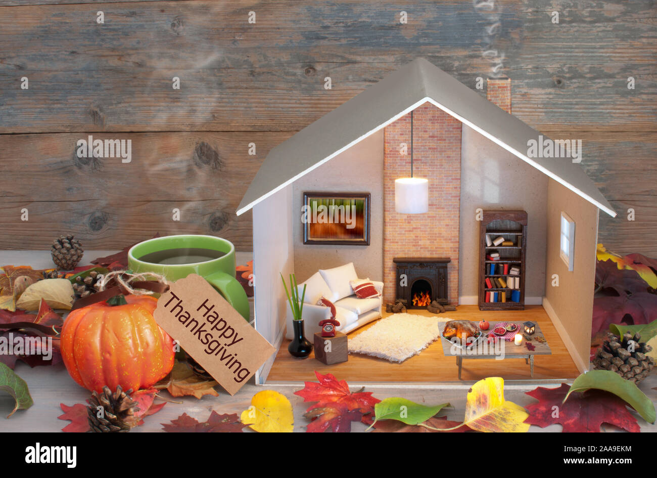 Thanksgiving home scene with label attached to miniature house living room and fireplace, and seasonal food laid out on a table Stock Photo