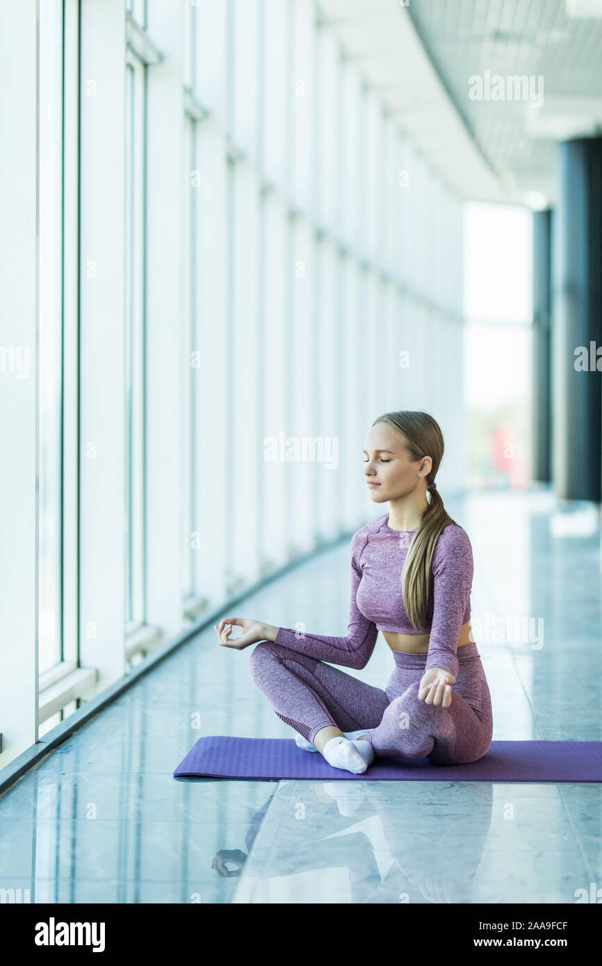 Yoga in studio. Attractive young woman sitting on lotus position on ...