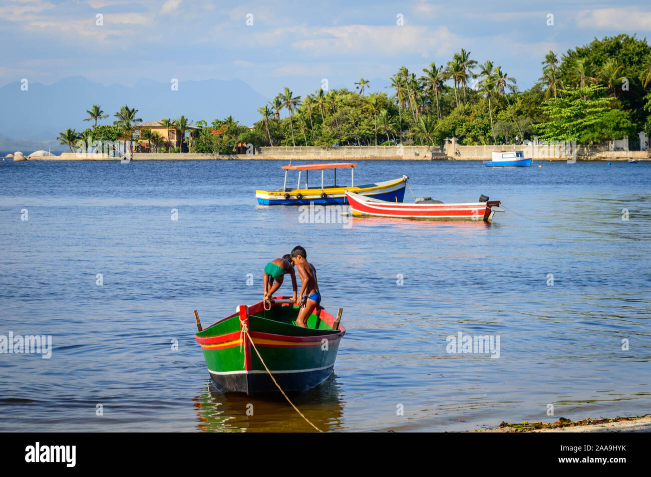 Two Brazilian boys in swimsuits playing in a wooden canoe at Paquetá Island, Rio de Janeiro, Brazil. Stock Photo