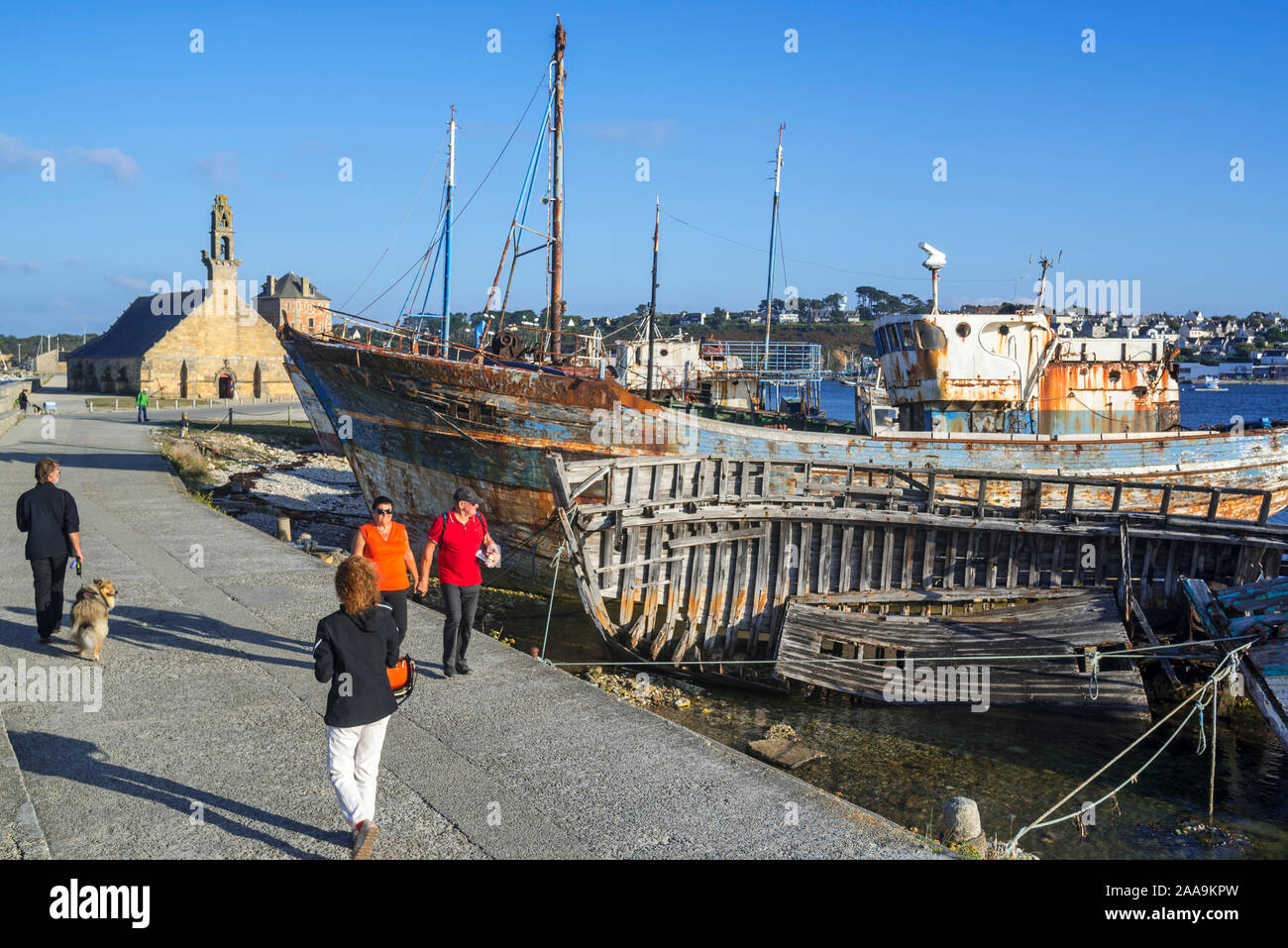 Tourists visiting wrecks of old wooden trawler fishing boats / lobster boats in the harbour / port of Camaret-sur-Mer, Finistère, Brittany, France Stock Photo