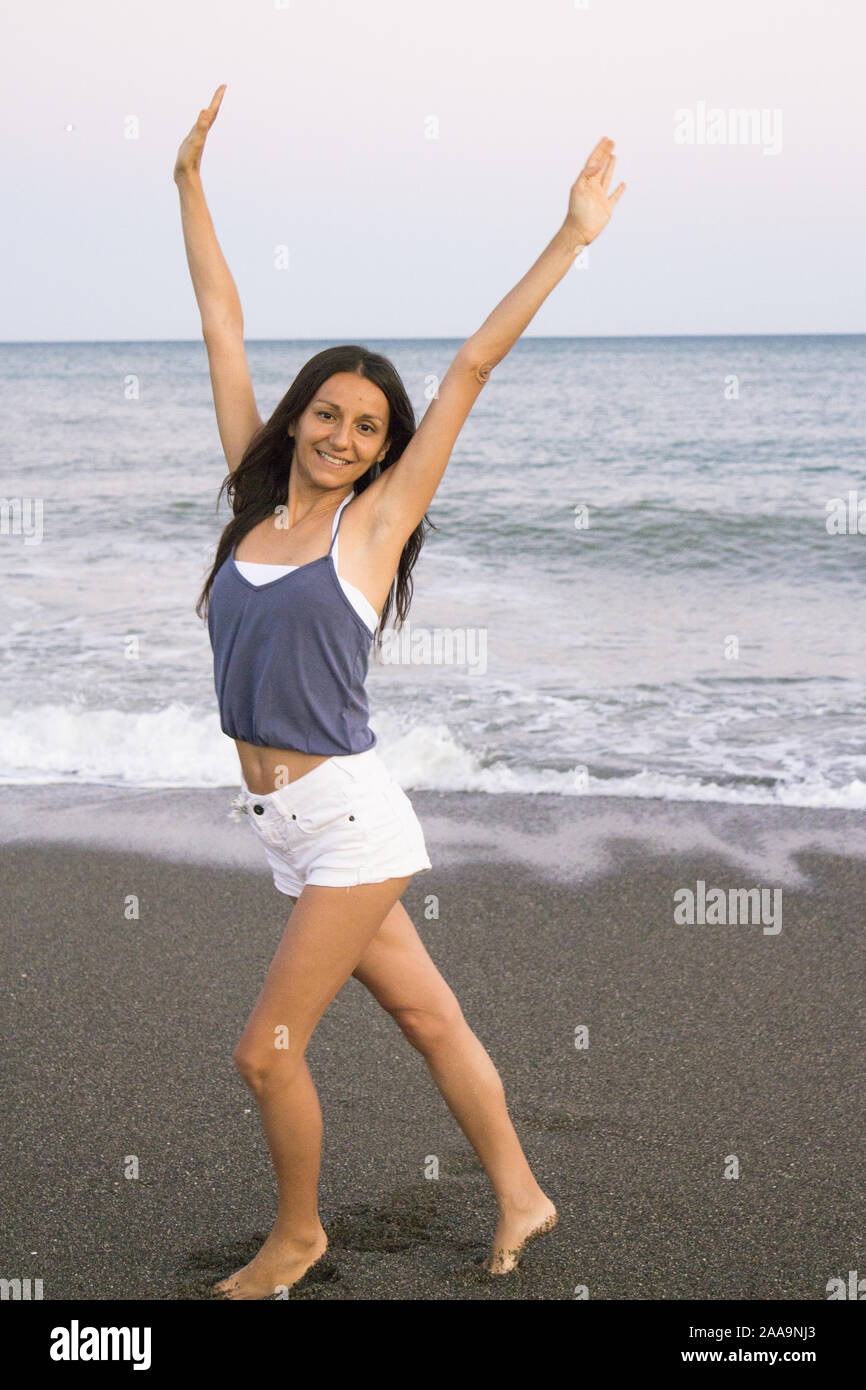 Mujer joven en la playa en actitud muy positiva y feliz. Precioso atardecer  Stock Photo - Alamy
