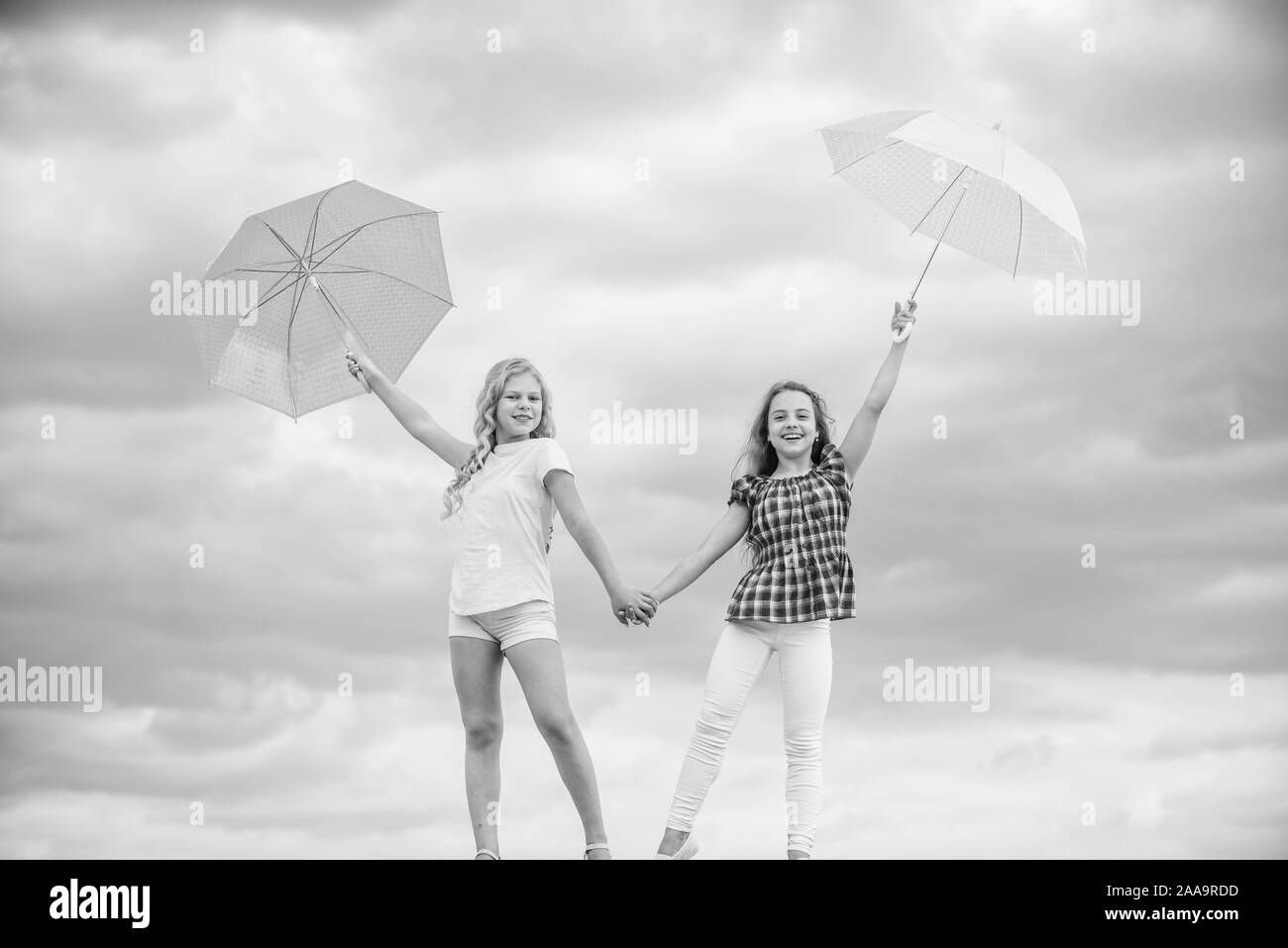 Exploring the world together. autumn season. rainy weather forecast. fall kid fashion. protected at autumn day. happy small girls with umbrella. positive and bright mood. best friends. school time. Stock Photo