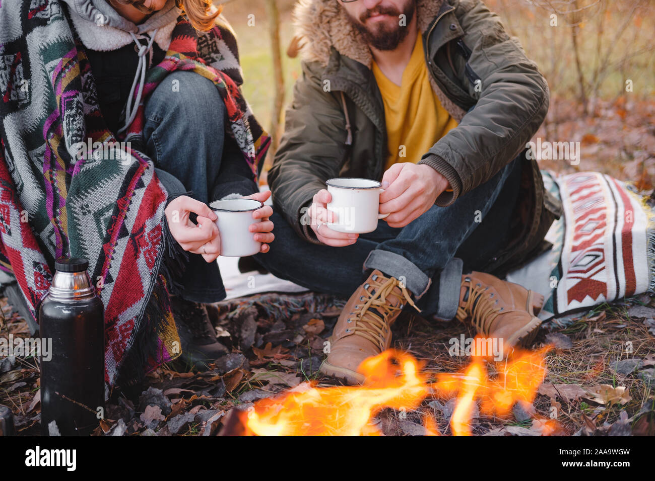 Two people having a lovely time outdoors with a pet in autumn. Man and woman in warm clothes sit outdoors together with their dog on a lovely chilly d Stock Photo