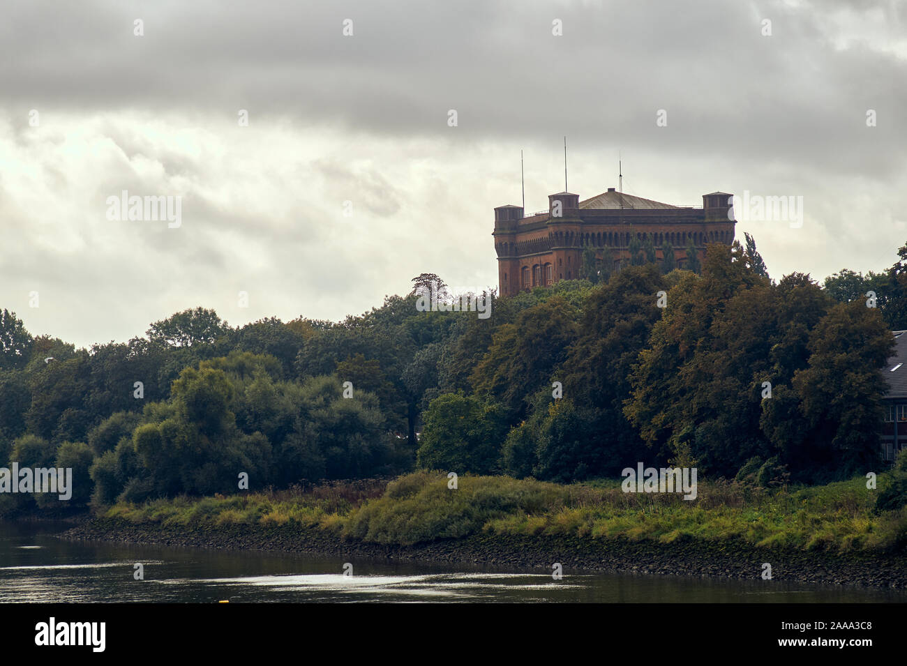 ancient castle beyond the river and trees Stock Photo