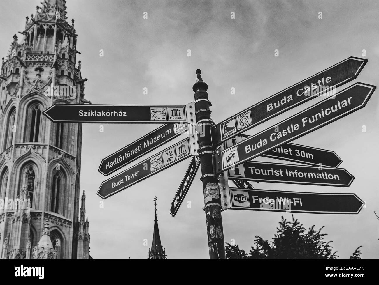 Black and white photo of tower of Matthias Church and direction signpost. Stock Photo