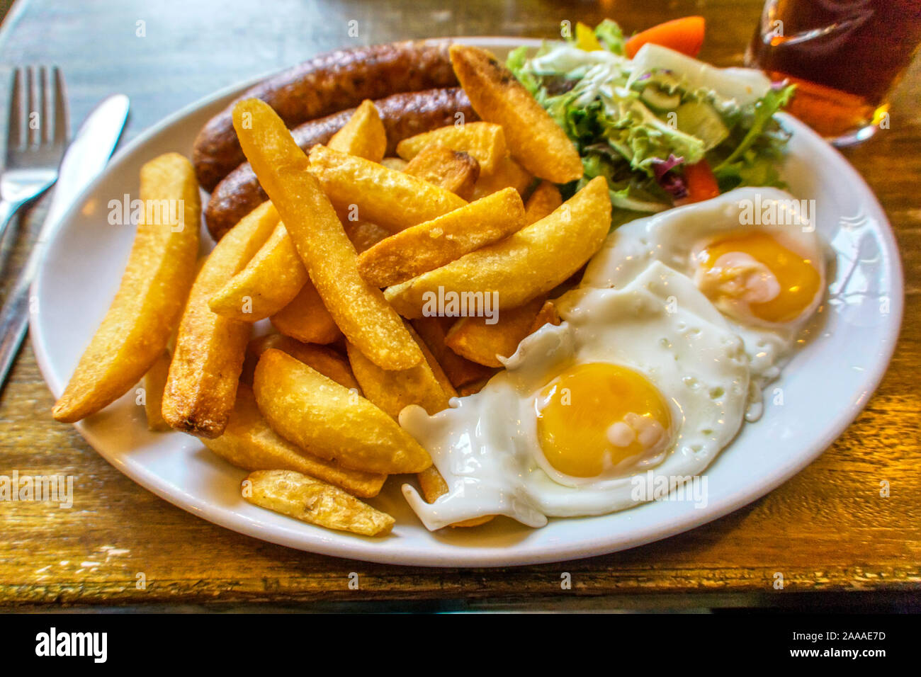 A typical English pub meal of sausage, egg and chips. Stock Photo