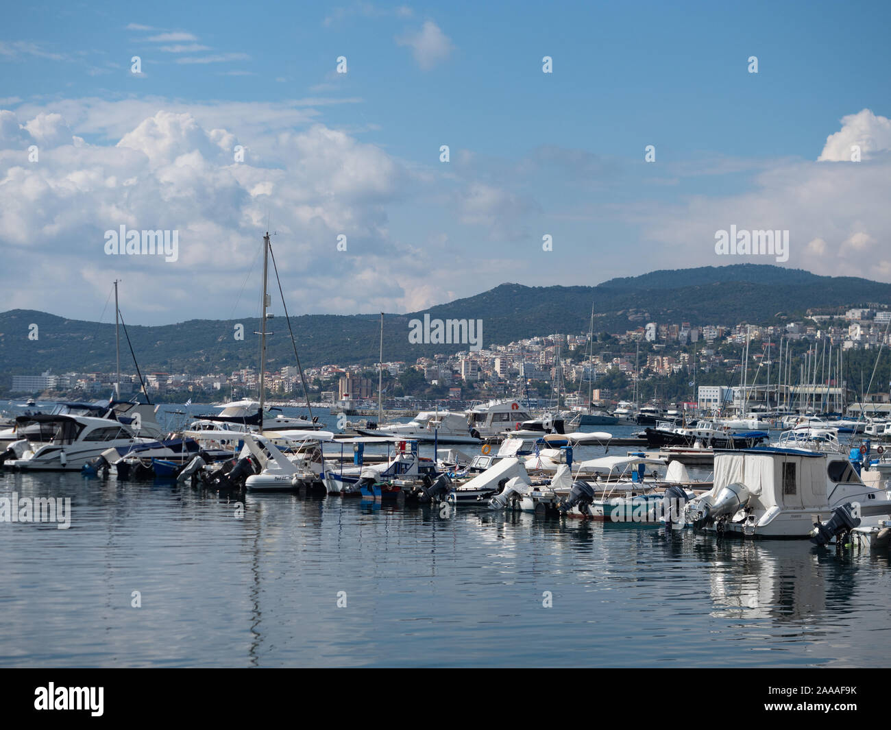 Bay of Kavala in the Aegean Sea with rows of powerboats and sailboats docked in the harbor and the city of Kavala and mountains in the background Stock Photo