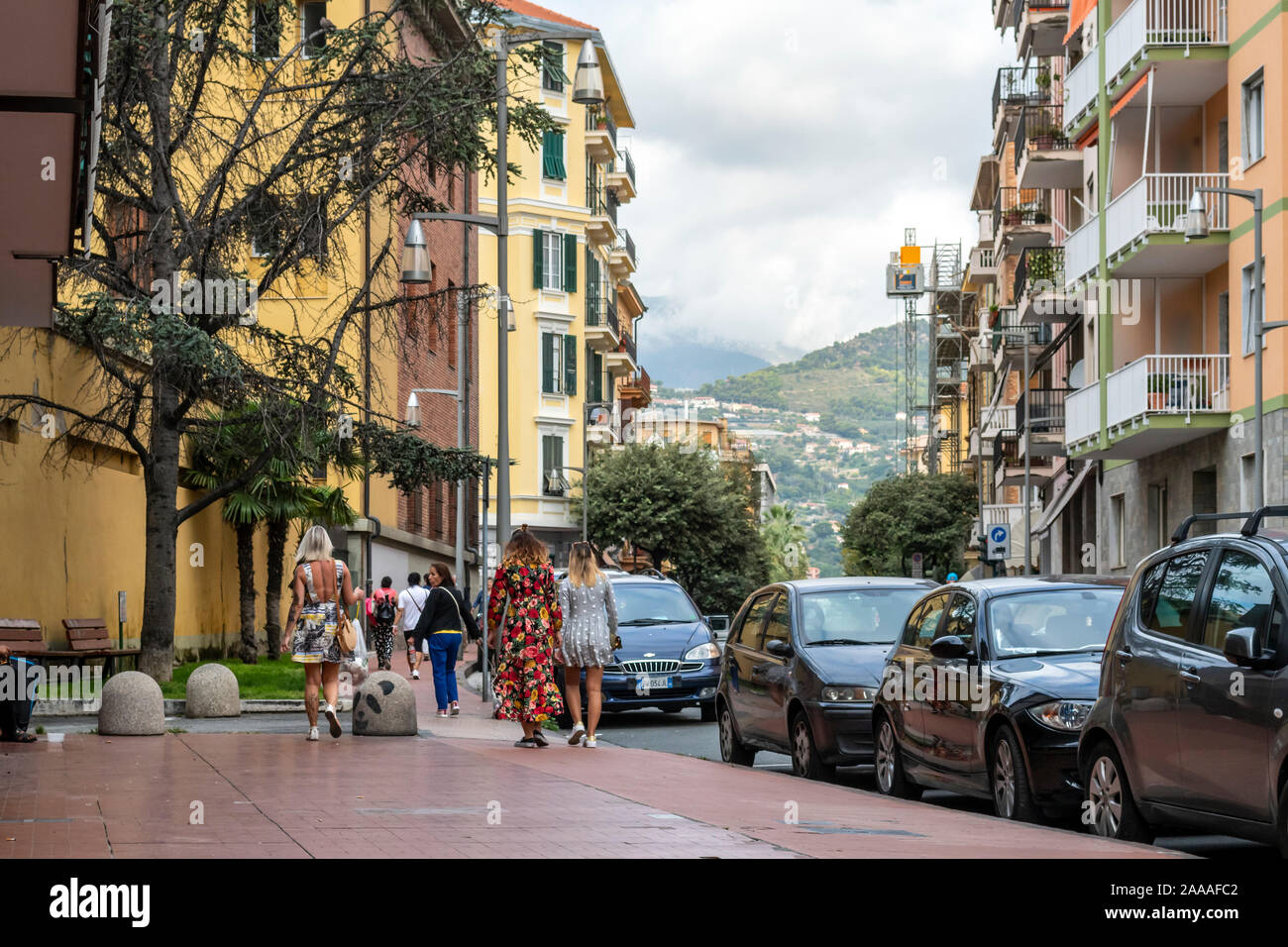Italian women with colorful print dresses walk along a residential street in the Ligurian city of Ventimiglia, Italy, on the Italian Riviera. Stock Photo