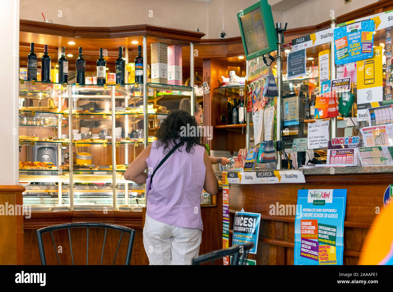 A female customer buys lottery tickets at a Tabacchi shop in the Ligurian city of Dolceacqua, Italy Stock Photo