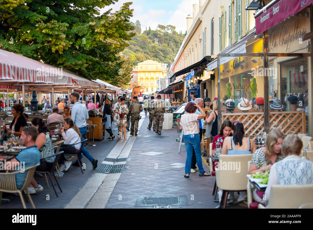 French soldiers in military fatigues patrol the Cours Saleya Old Town area in Nice, France as diners enjoy an early dinner on the French Riviera. Stock Photo