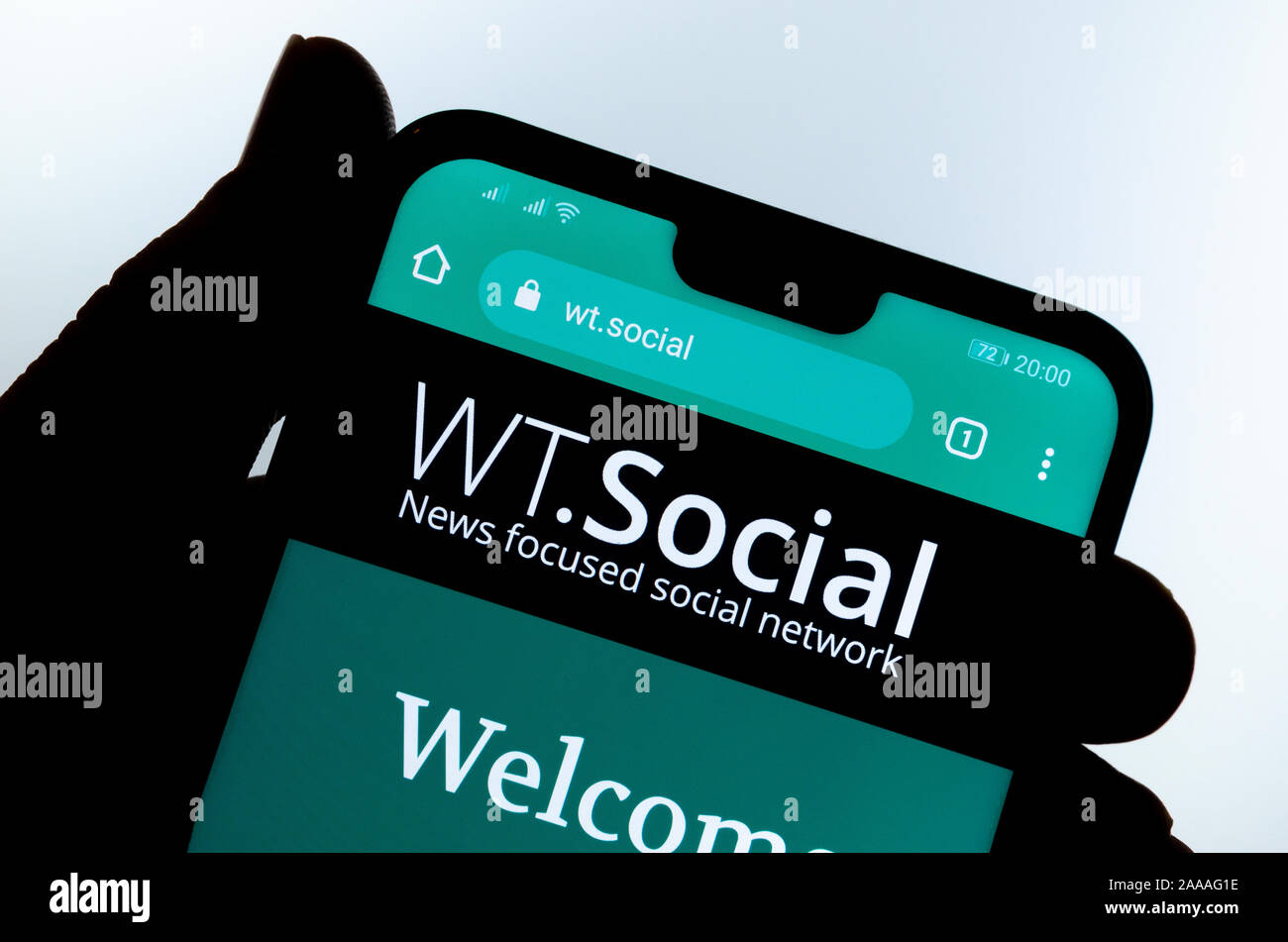 WT.Social website on the smartphone hold by a silhouette of a hand. WT:Social is news focused social network from Wikipedia founder. Stock Photo