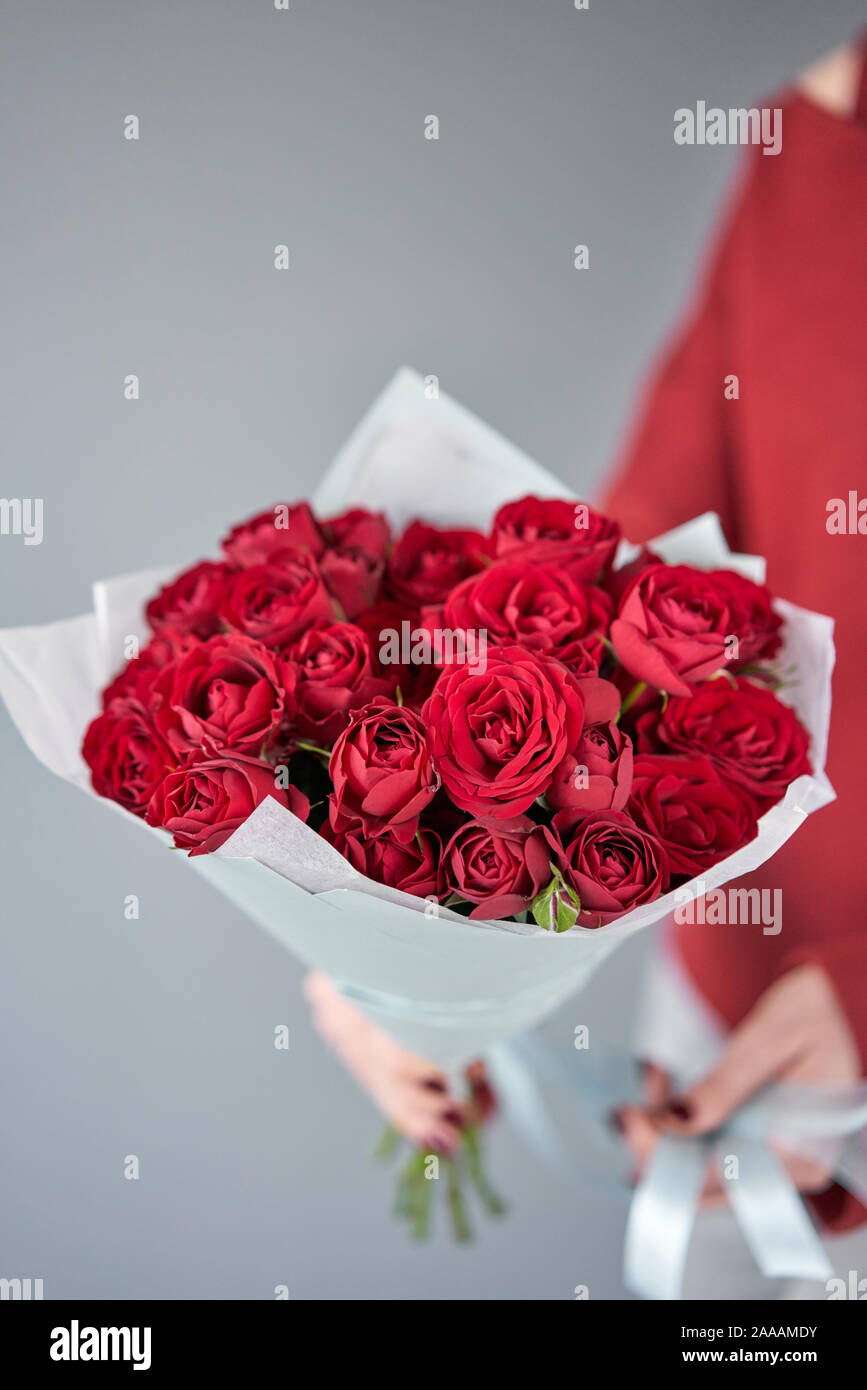 Red mono bouquet of Bush roses in womans hands. European floral shop. the work of the florist at a flower shop. Delivery fresh cut flower. Stock Photo