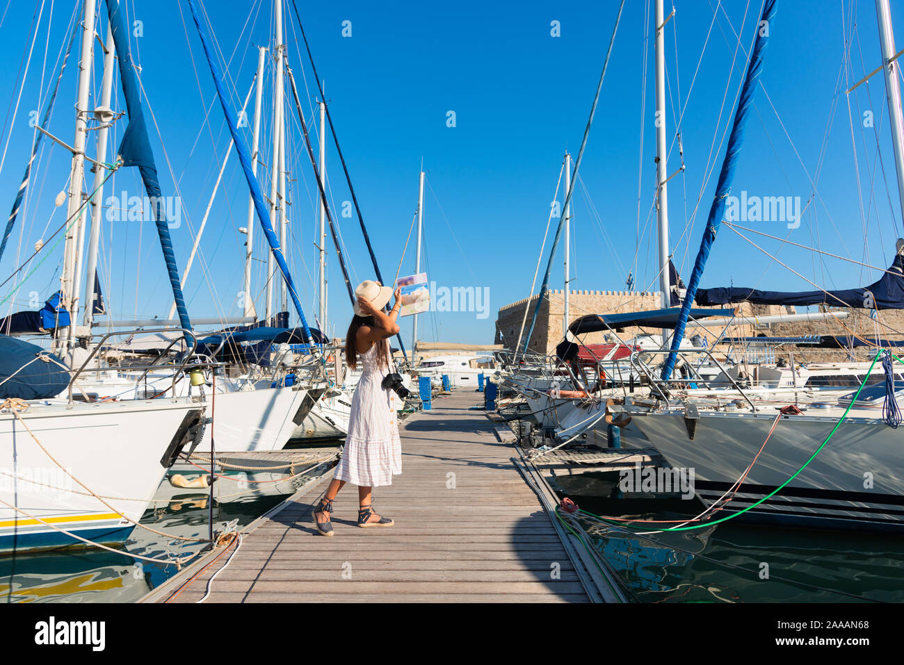Elegant young tourist visitor woman walking on a sightseeing tour at Heraklion Venetian port, Crete, Greece . Venetian fortress Rocca A Mare or Stock Photo