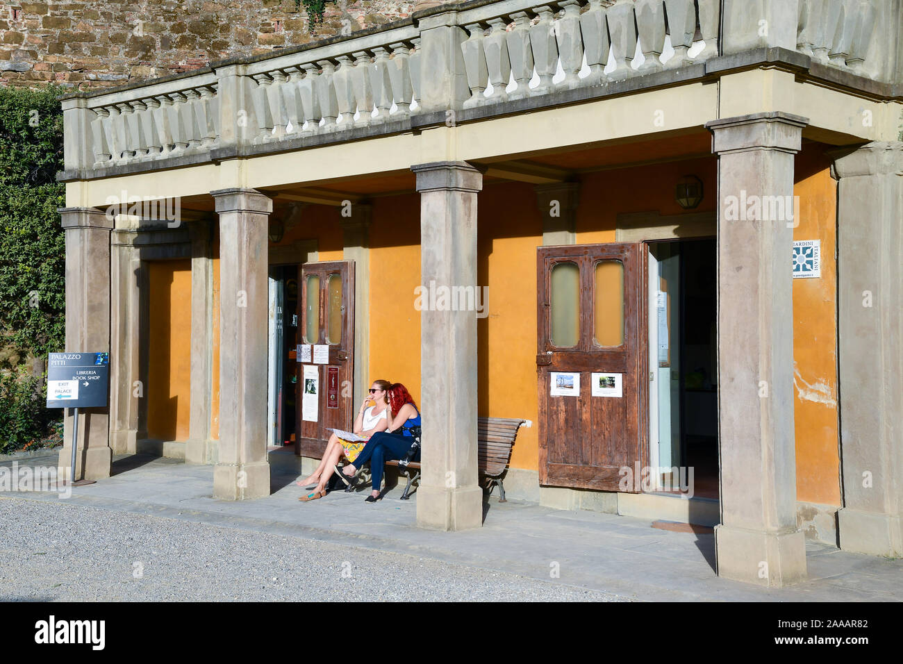 Two tourist friends resting on a bench in the Boboli Gardens of Palazzo Pitti in the historic centre of Florence in a sunny day, Tuscany, Italy Stock Photo