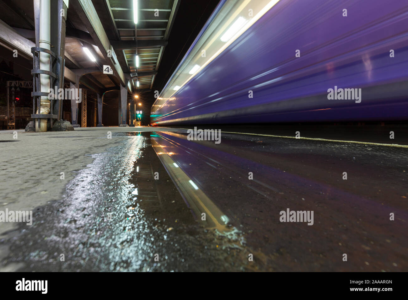 Arriva Northern rail class 142 pacer train departing from Preston railway station leaving a light trail and reflection at night Stock Photo