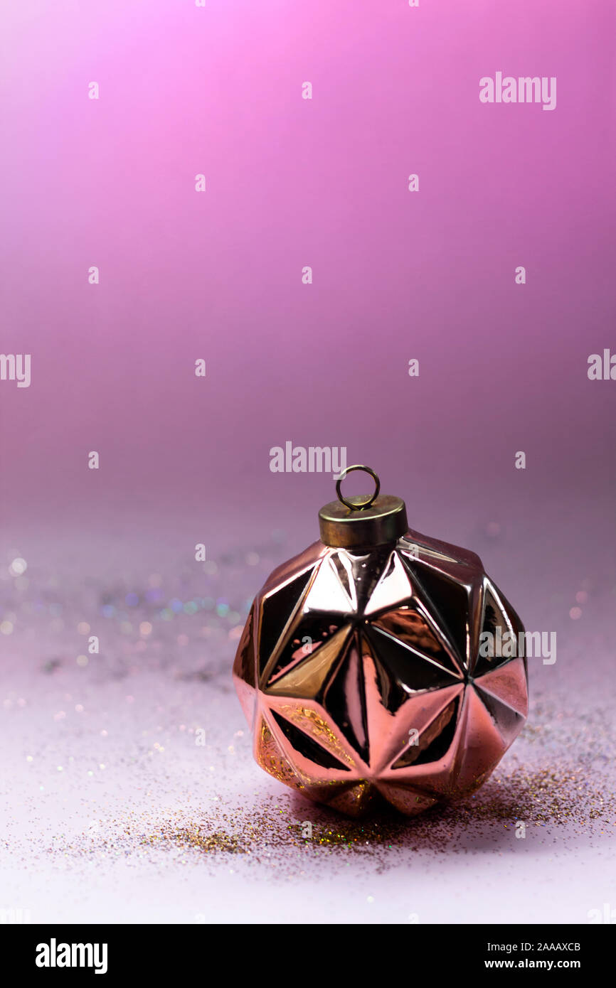 Modern geometric rose gold Christmas ball and sparkles on pink background. Stock Photo