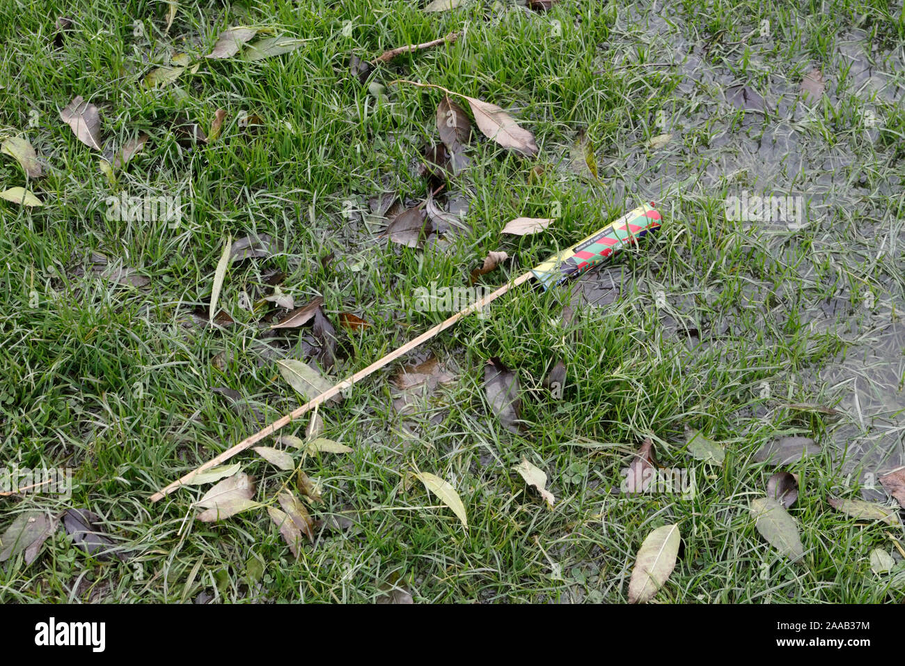 Discarded firework rocket on the ground,  damp playing field Stock Photo