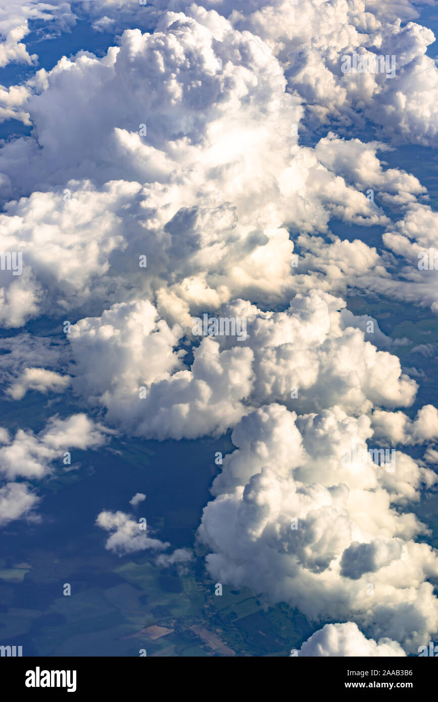 Big and fluffy clouds, top view. Cascades of white clouds in a blue sky haze. Stock Photo