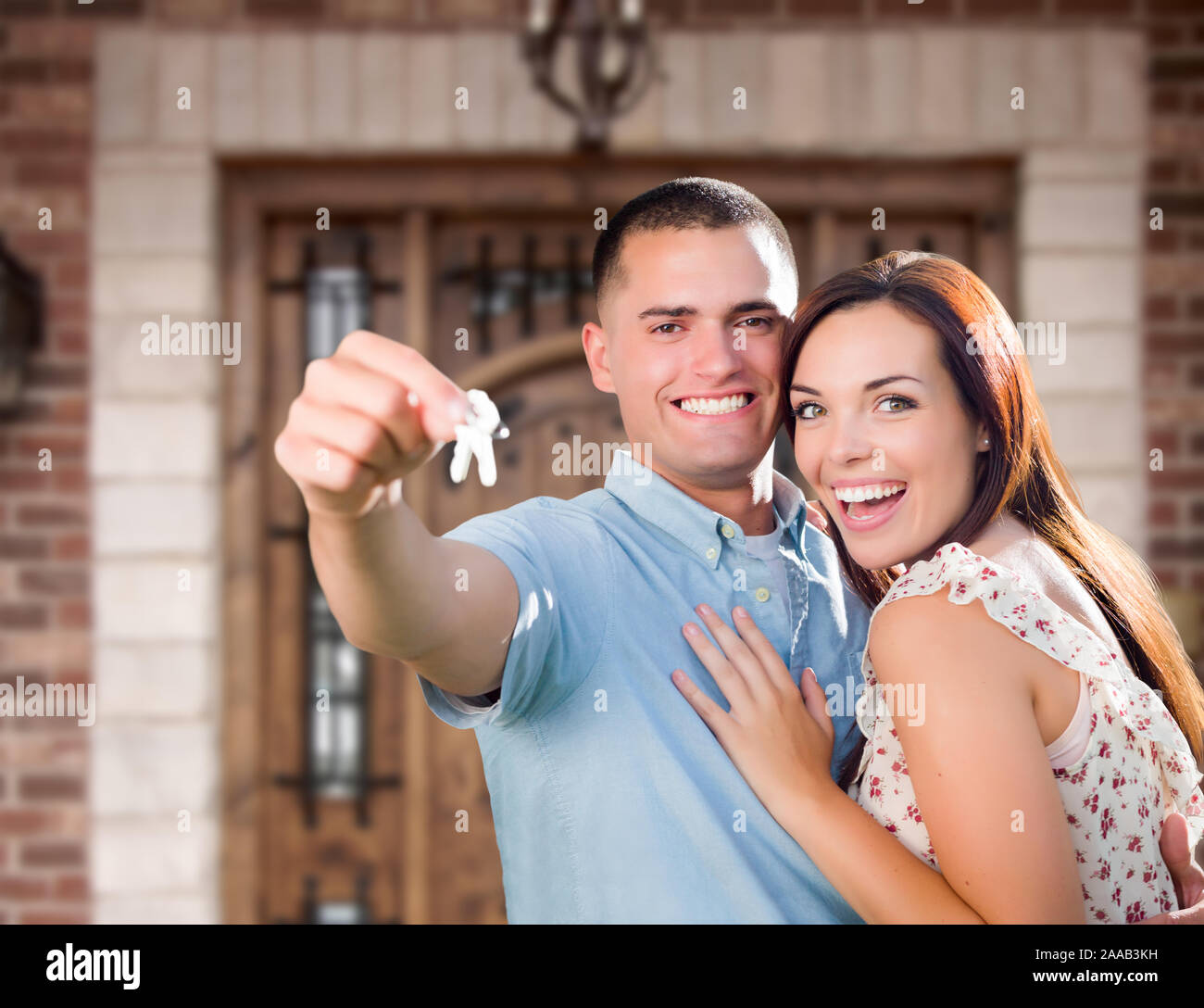 Young Military Couple In Front of Front Door of New House Holding Keys. Stock Photo