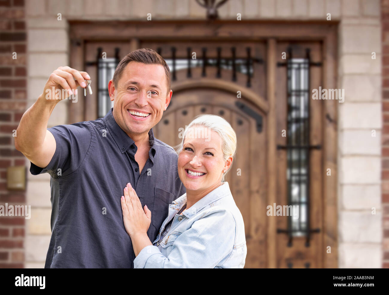 Young Couple In Front of Front Door of New House Holding Keys. Stock Photo