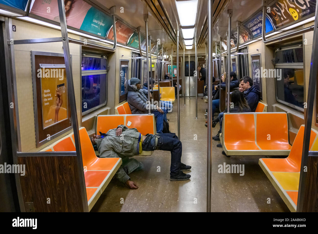 New York, USA, 9 November 2019.  Passengers ignore an indigent man sleeping in the subway in New York City.   Credit: Enrique Shore/Alamy Stock Photo Stock Photo