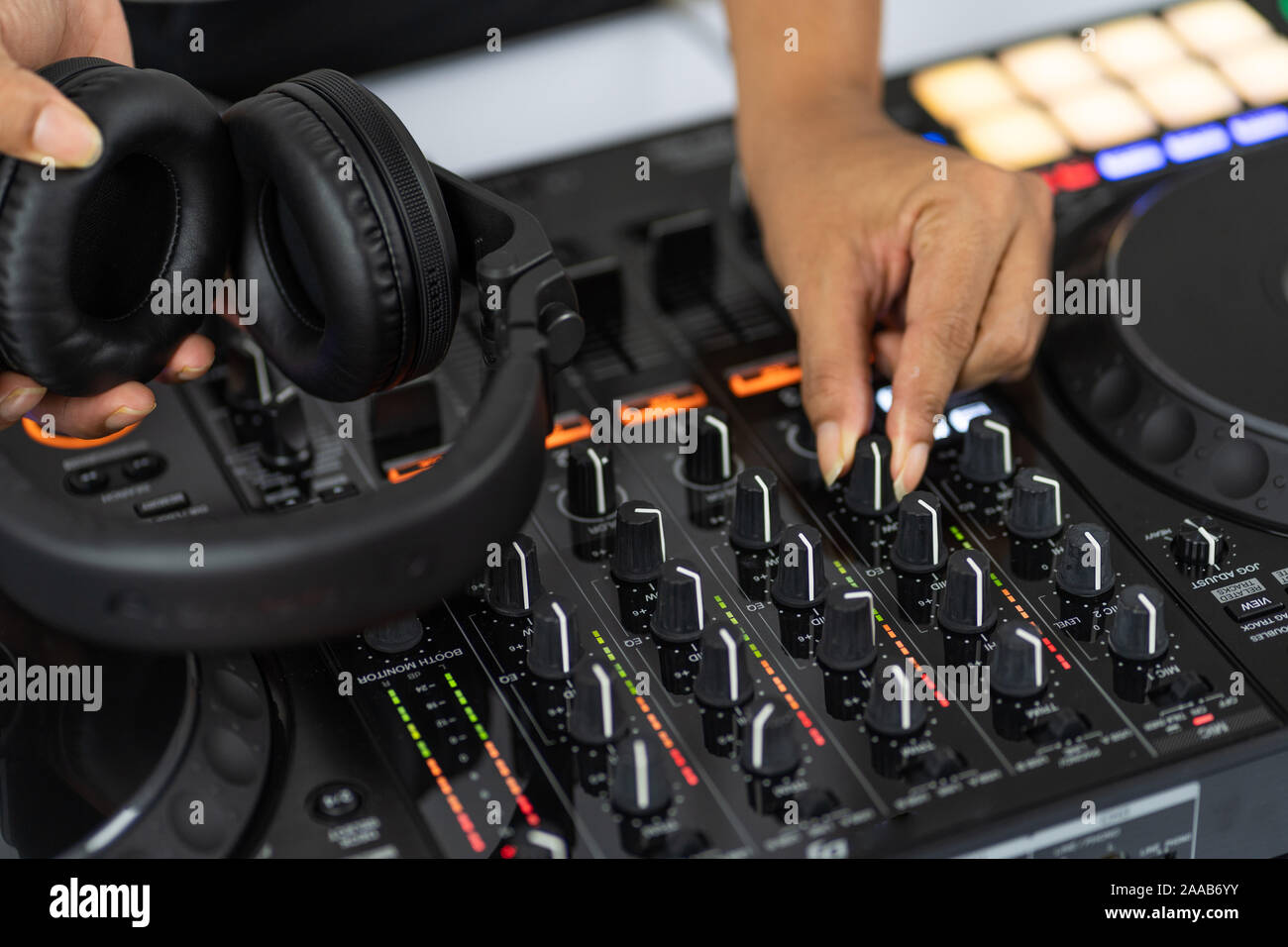 Hands of DJ mixing tracks on professional sound mixer.Fashionable rings on fingers of girl disc jockey playing music.Closeup,knobs and regulators in Stock Photo