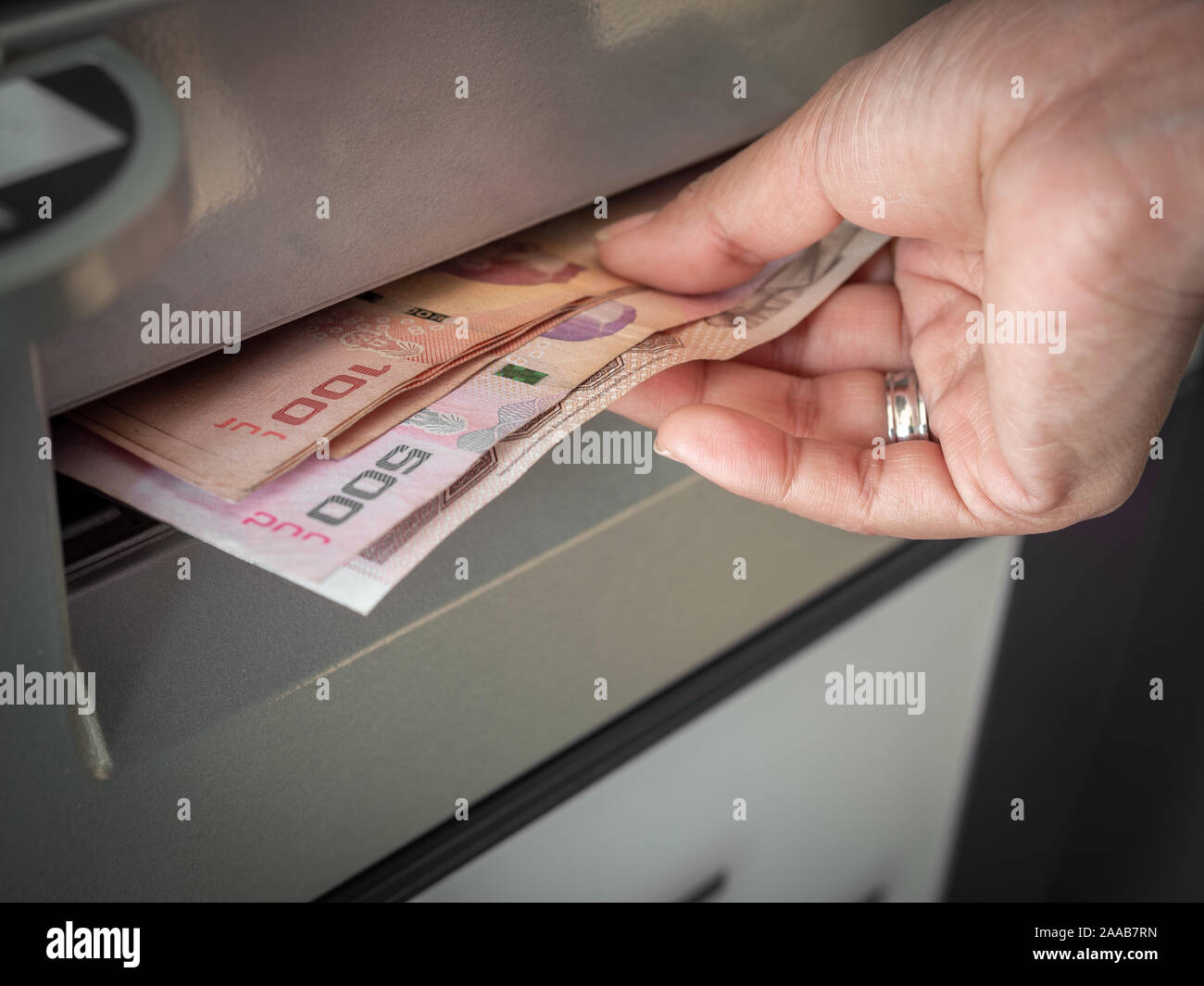 Closeup hand withdraw money, the banknotes thai baht from ATM machine