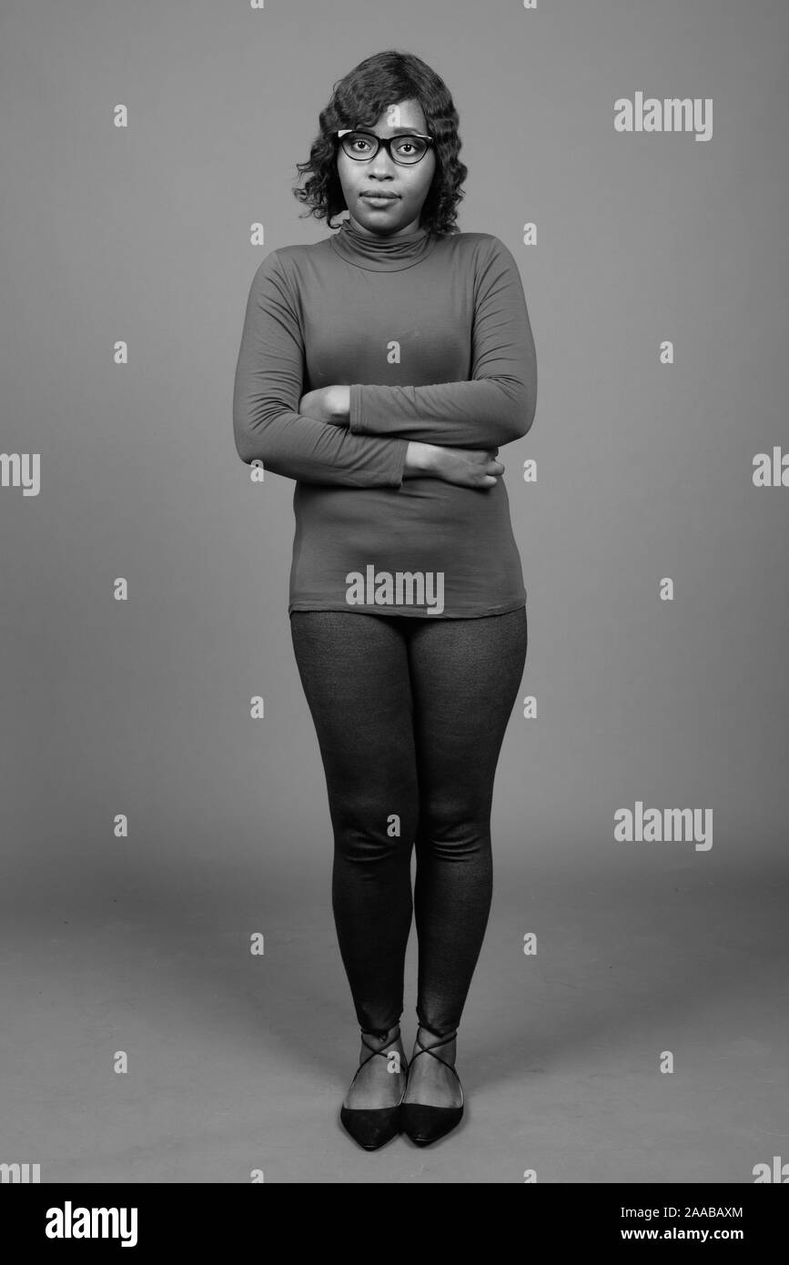 Young beautiful African woman wearing eyeglasses against gray background Stock Photo