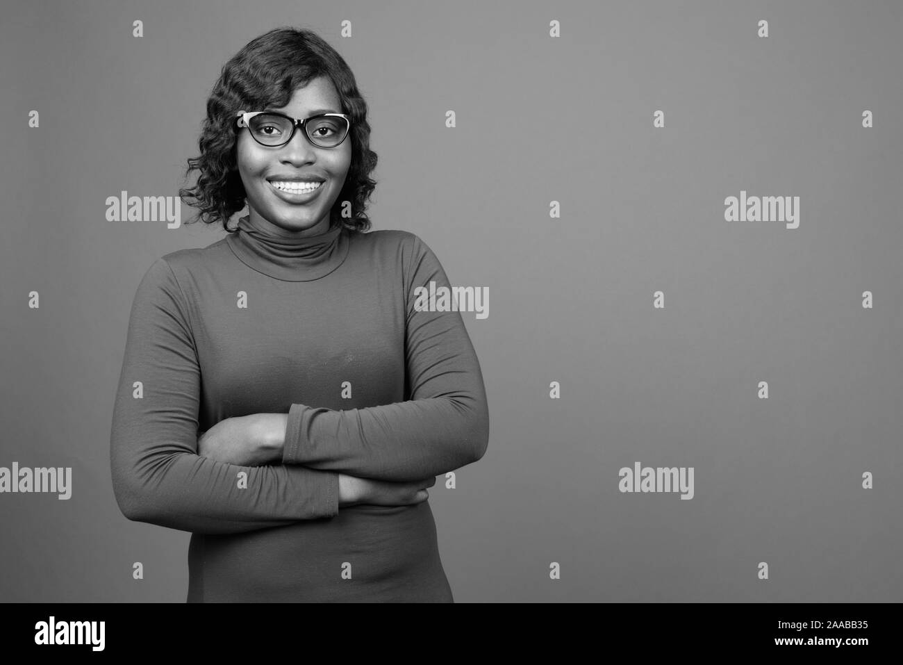 Young beautiful African woman wearing eyeglasses against gray background Stock Photo