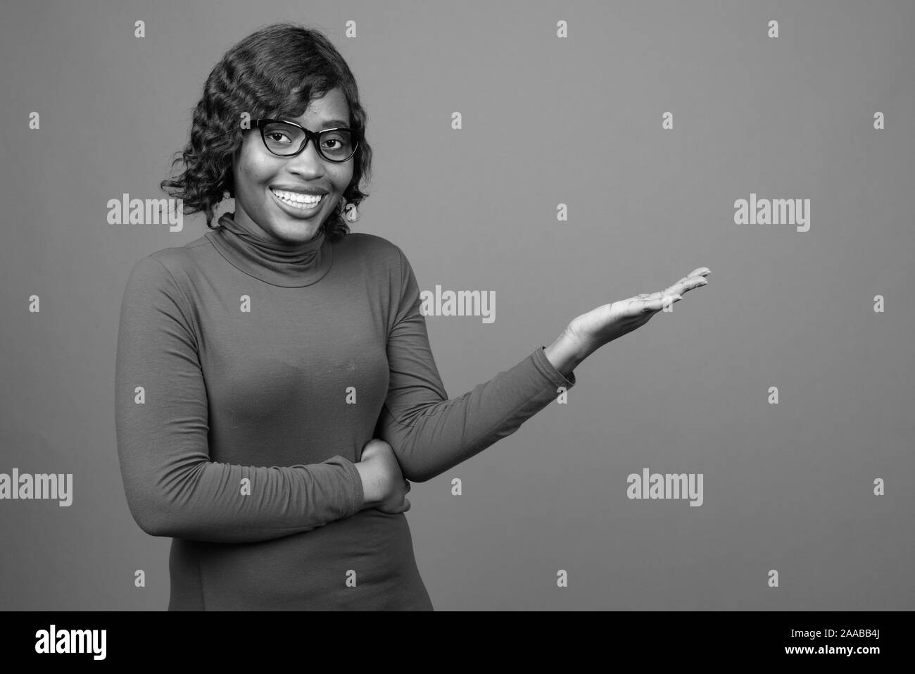 Young beautiful African woman wearing eyeglasses against gray background Stock Photo