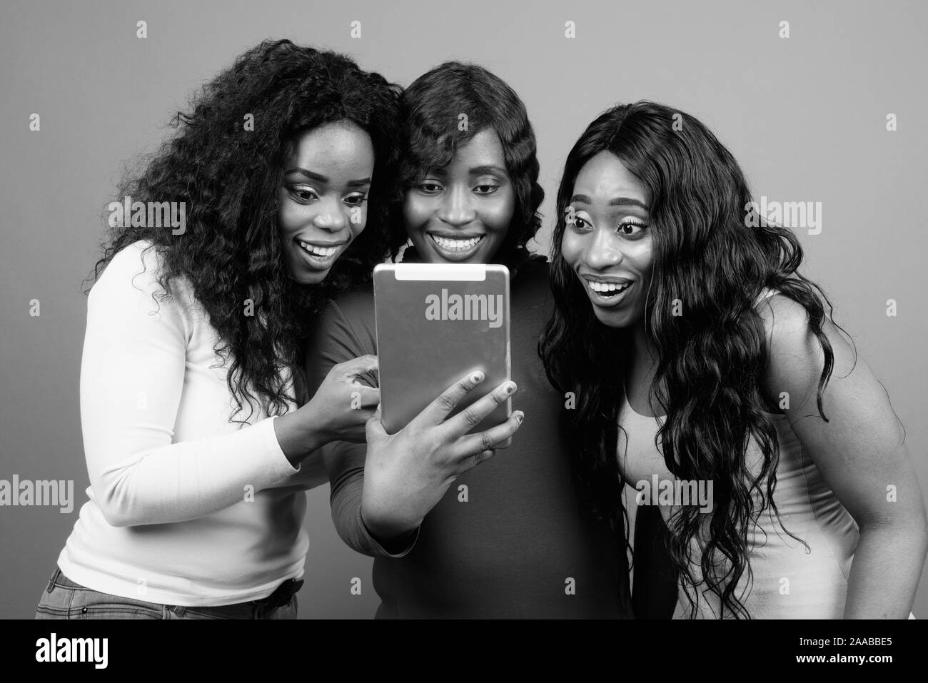 Young beautiful African twin sisters and friend against gray background Stock Photo