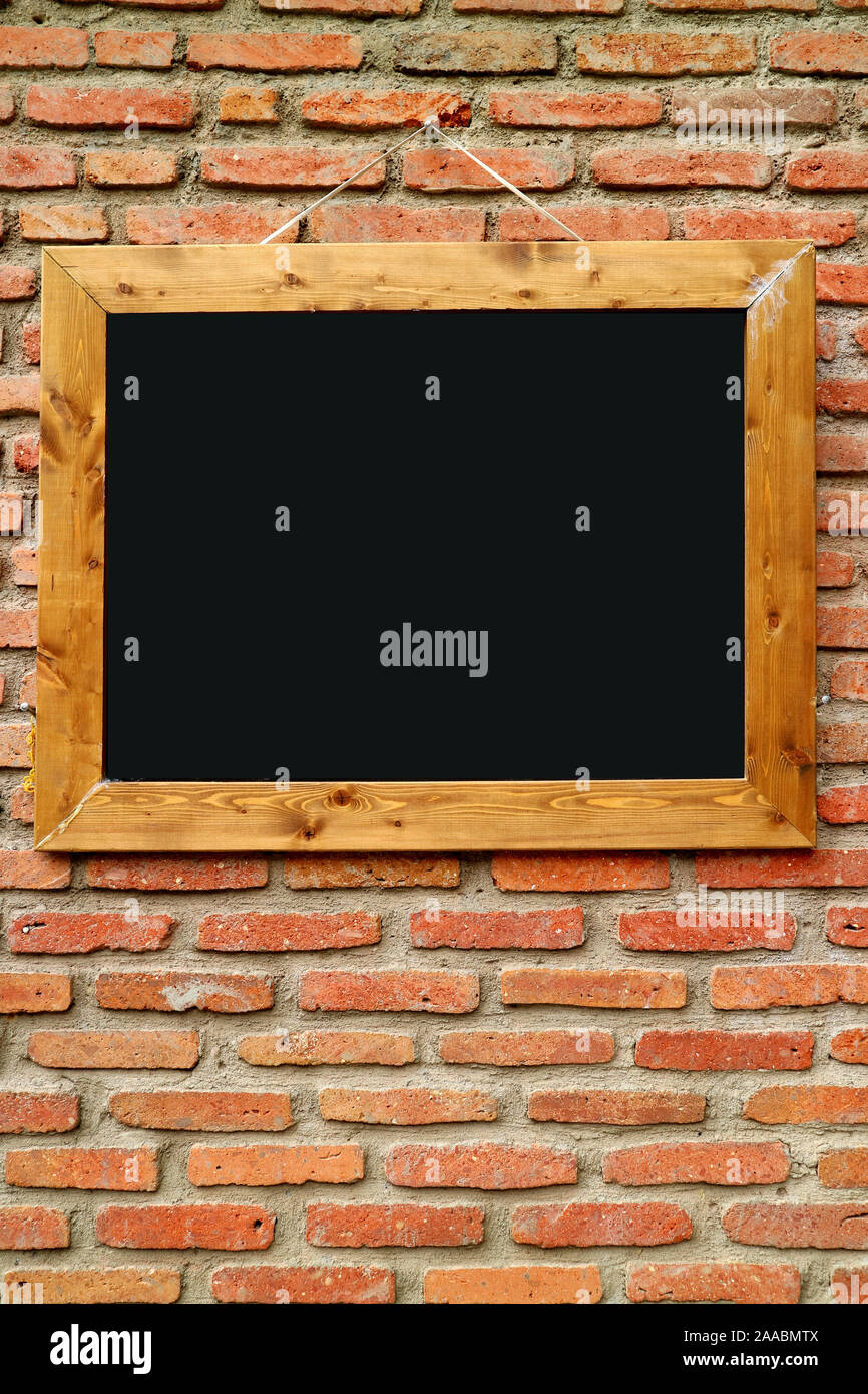 Vertical image of wooden frame blackboard on retro brick wall Stock Photo -  Alamy