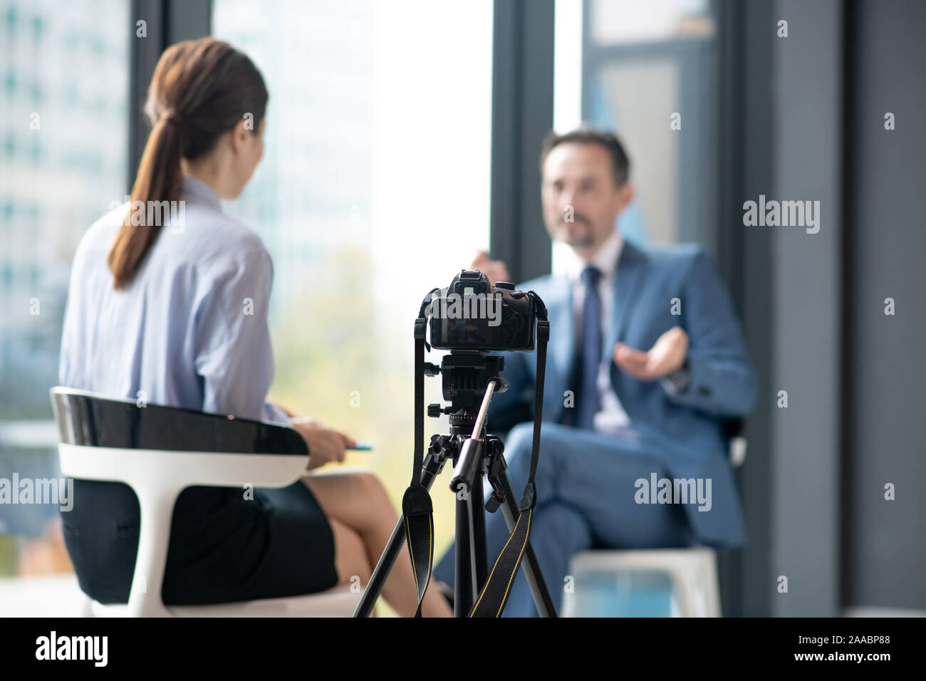 Camera filming businessman giving interview to famous journalist Stock Photo
