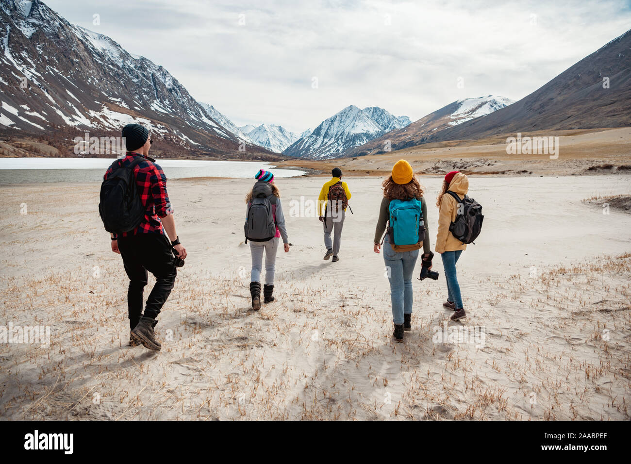 Group of young friends hikers are walking in mountains valley Stock Photo