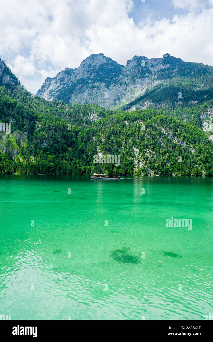 A tourist boat is cruising over the green lake Koenigssee (Königssee) in Bavaria, Germany Stock Photo
