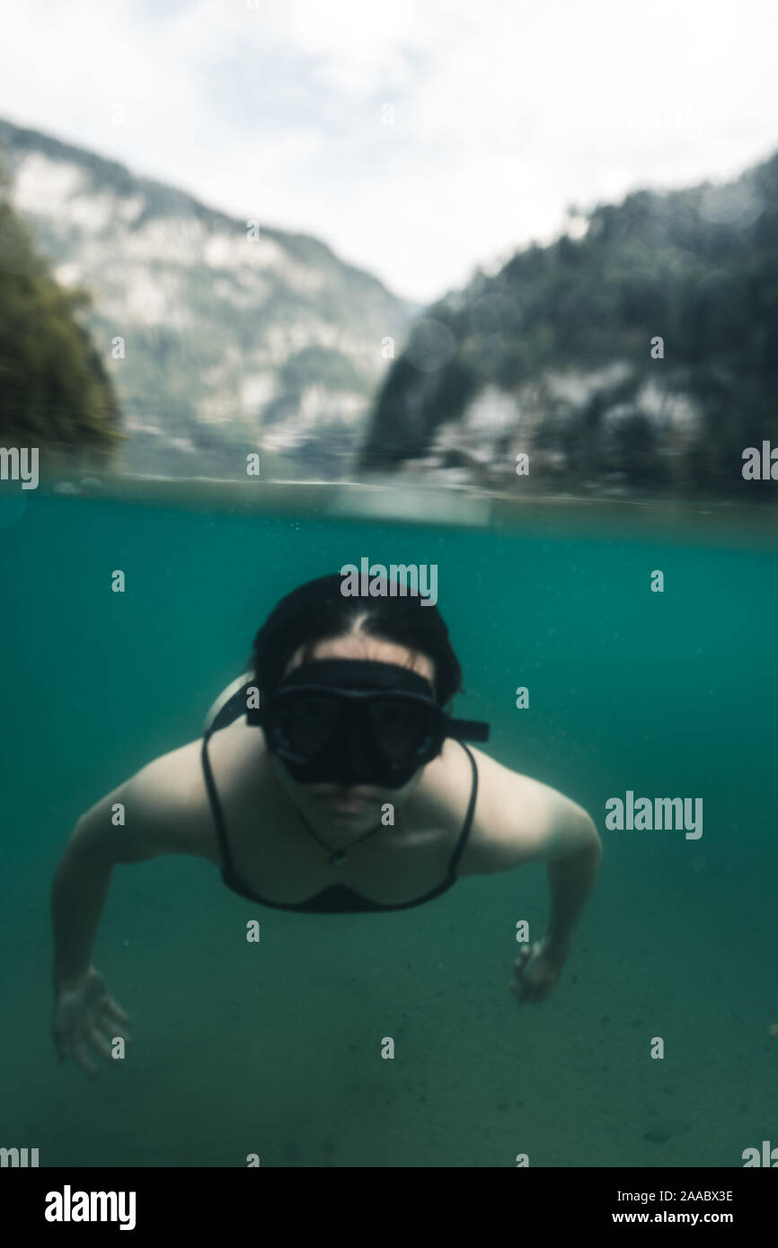Half half picture of girl swimming in a lake with a mask, in the background are the alps at the Koenigssee (Königssee) in the Berchtesgadener Land, Ba Stock Photo