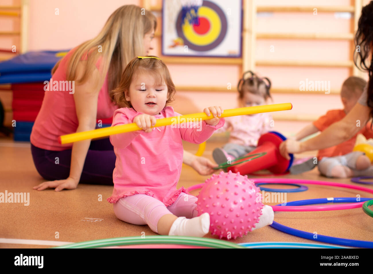 Kids and mentor playing with sport equipment in kindergarten gym Stock Photo