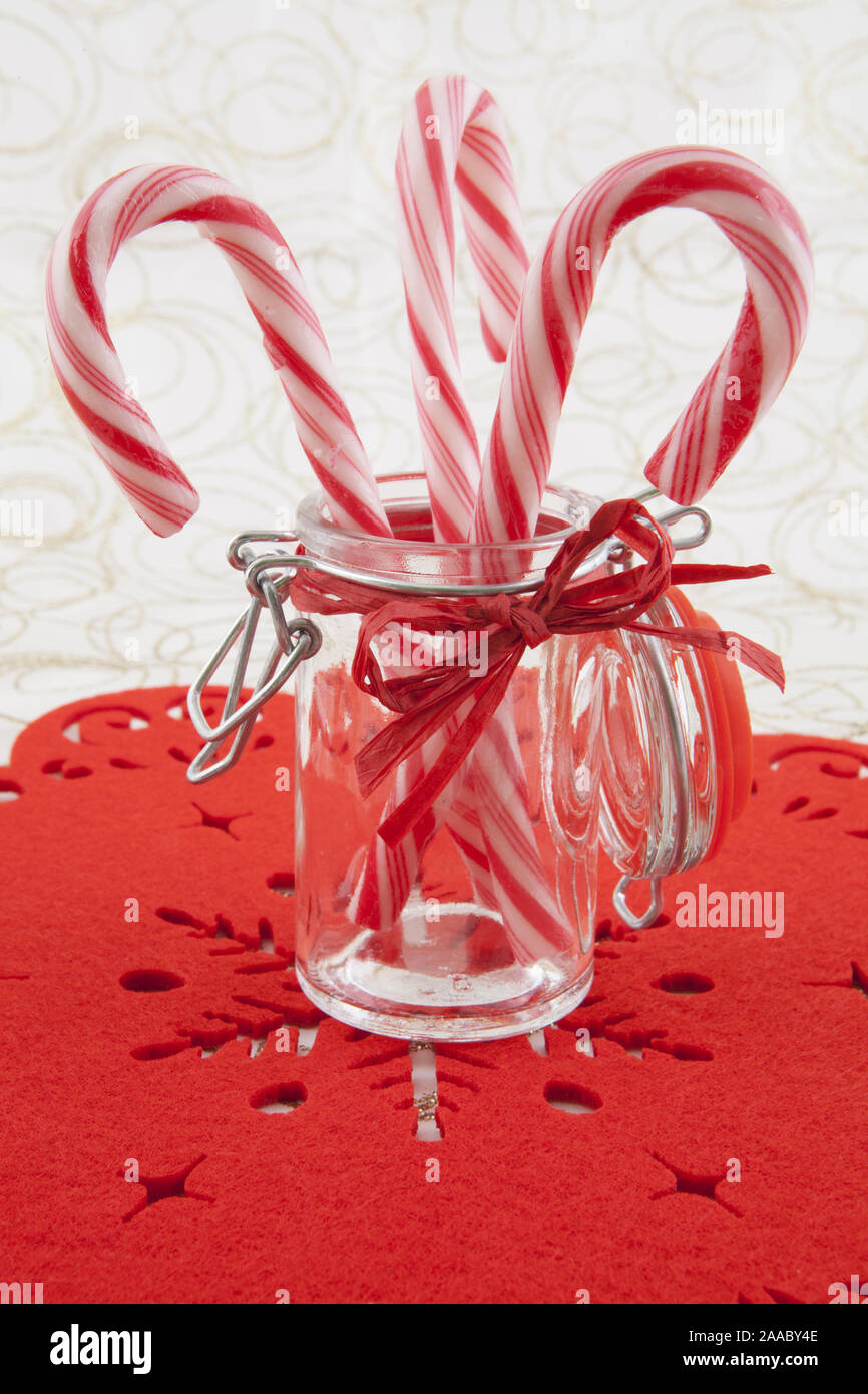 three traditional christmas candies cane in the glass on a white