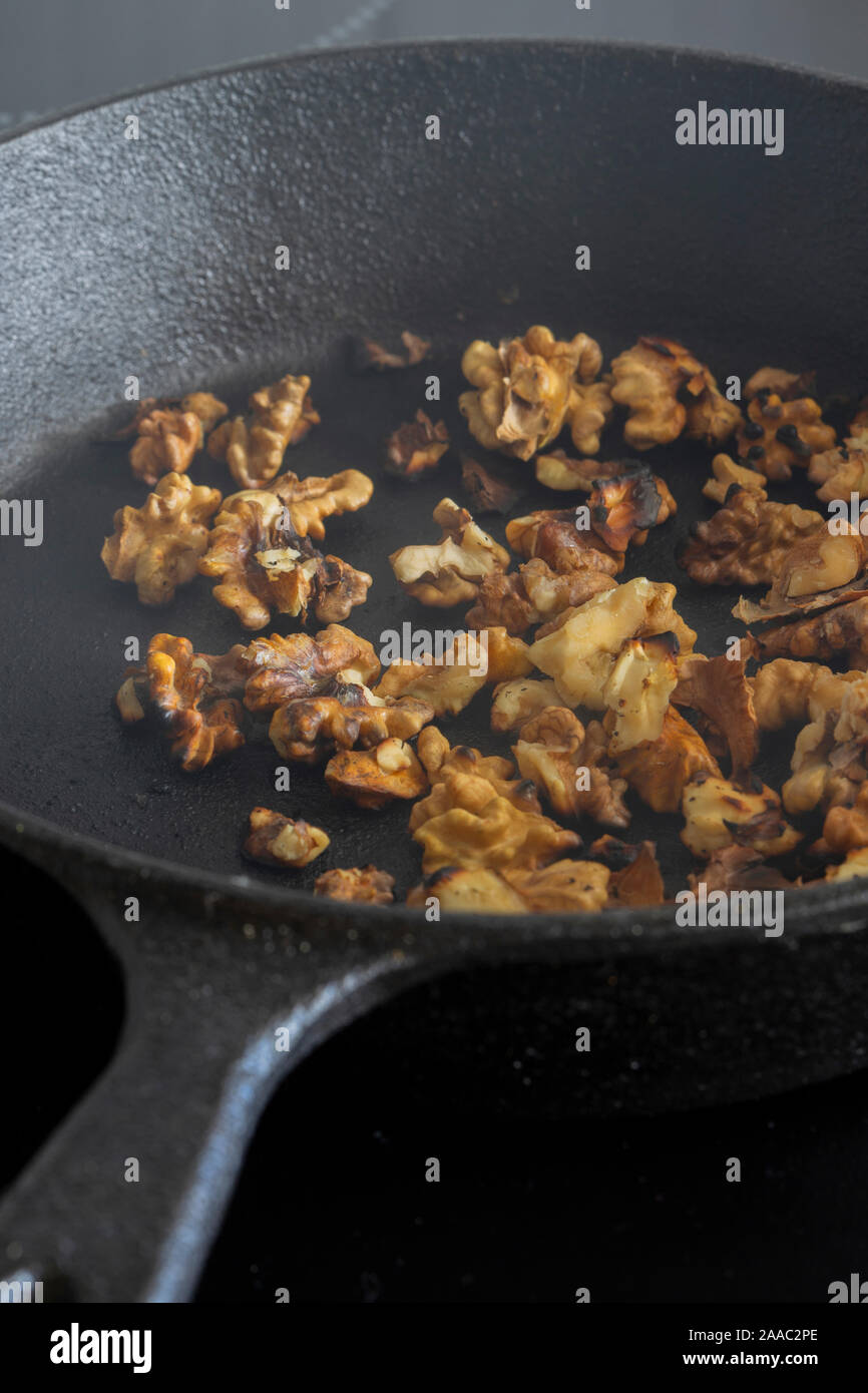 Walnuts Cooking In A Cast Iron Frying Pan On A Ceramic Hob Stove