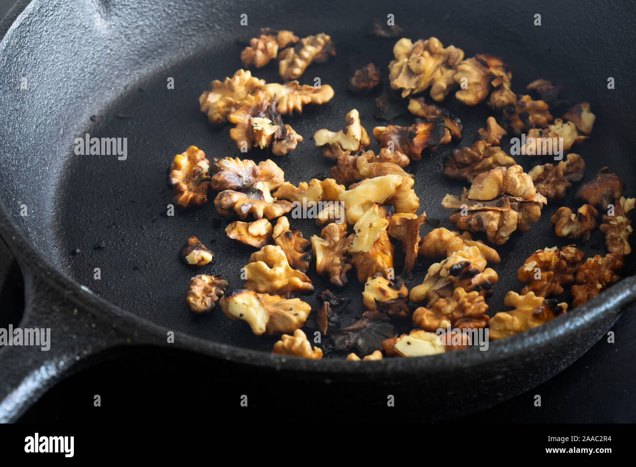 Walnuts Cooking In A Cast Iron Frying Pan On A Ceramic Hob Stove