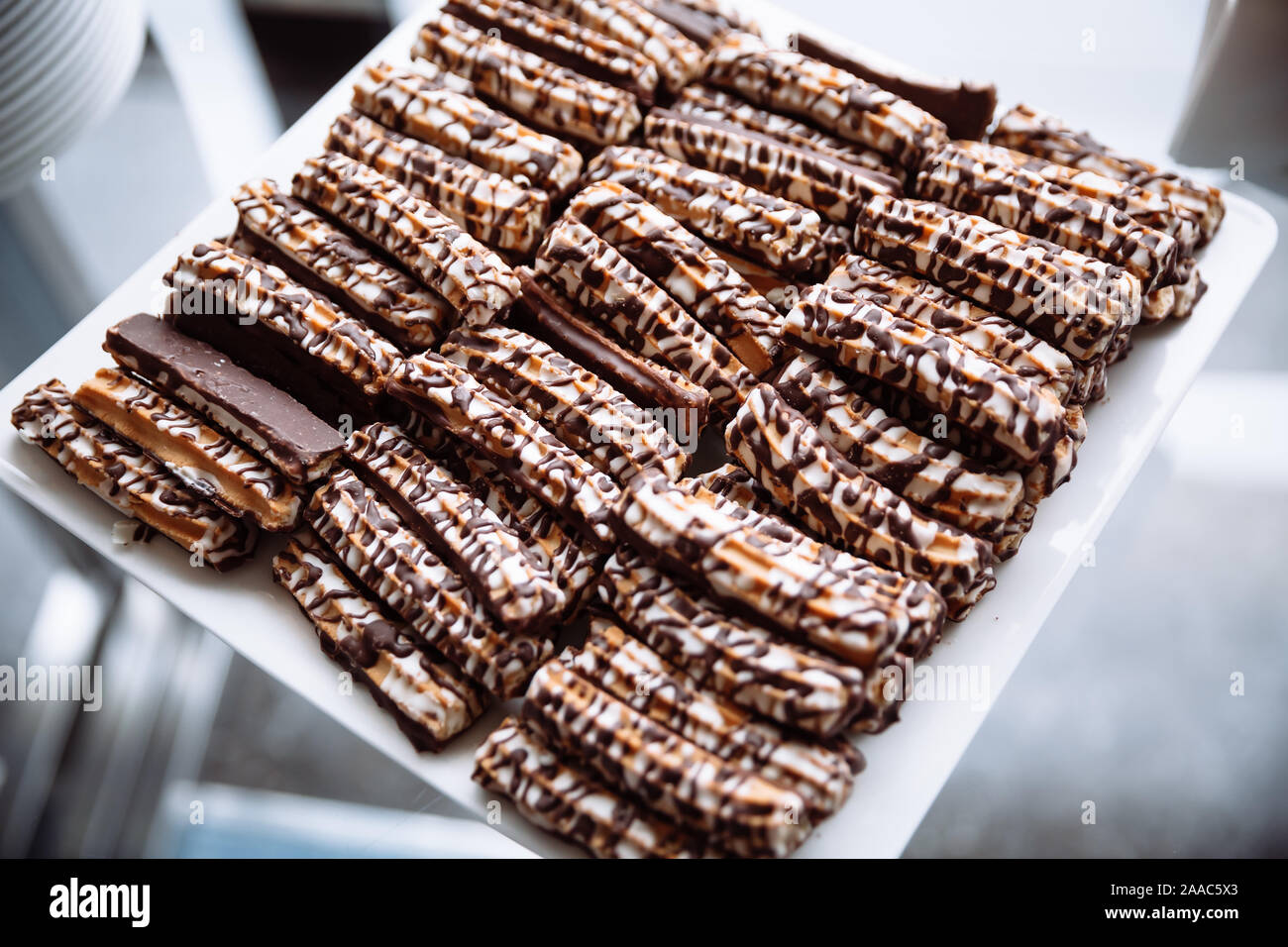 Shortbread cookies, drizzled with chocolate lying on a white, square plate. Stock Photo