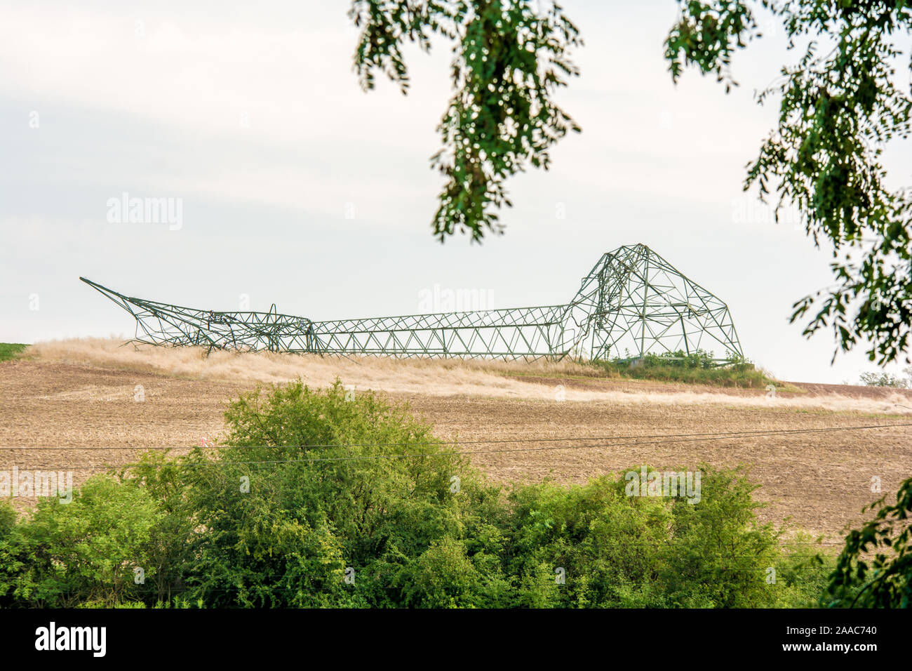 Stormed by a heavy storm power pole lying on a field Stock Photo